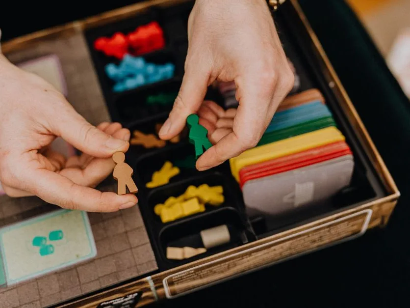 Board game components mid-play — meeples and dice on a printed board
