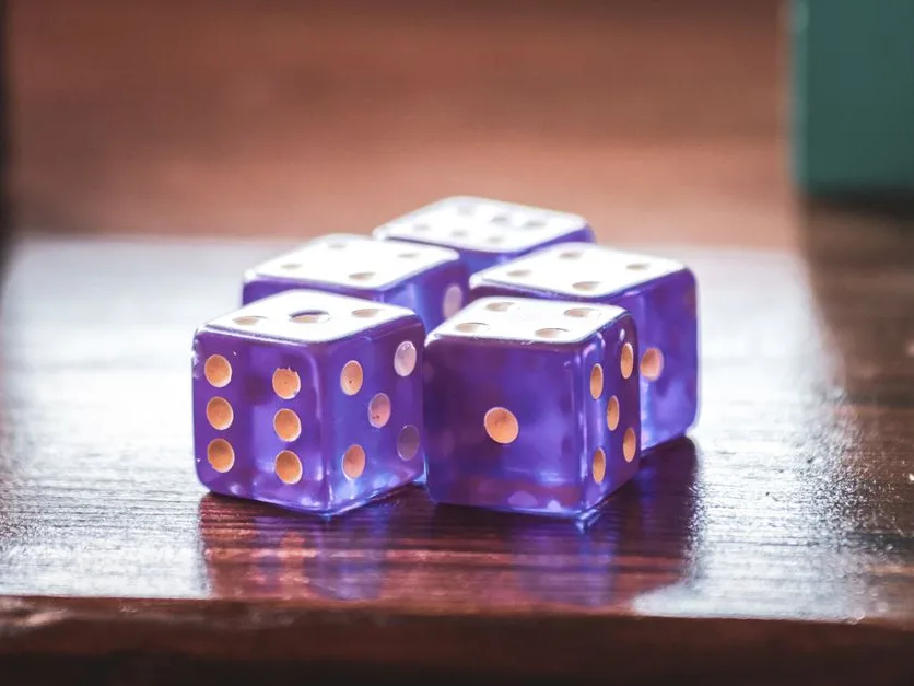 A set of translucent purple dice catching the light on a wooden table